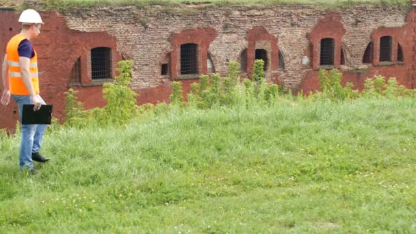 De man de historicus inspecteur loopt rond en inspecteert de oude historische gebouw, architect — Stockvideo