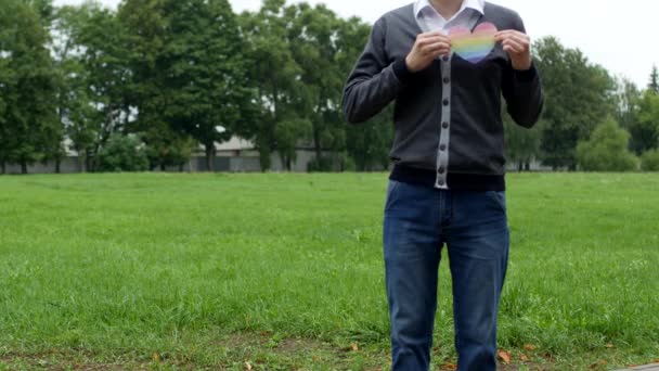 Un homme se tient dans la rue et tient un cœur sous la forme d'un drapeau de LGBT, l'homosexualité — Video