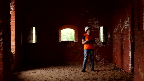 Um jovem inspetor verifica as paredes de um edifício antigo, historiador — Vídeo de Stock