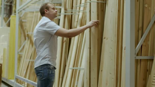 Comprador masculino elige tablas de madera en la tienda de materiales de construcción — Vídeo de stock