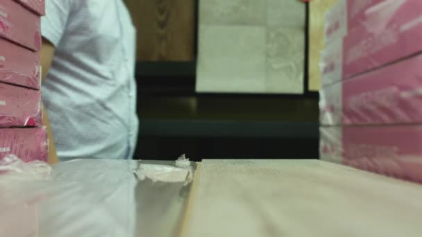 Customer checks the quality of the laminate flooring in hardware store — Stock videók