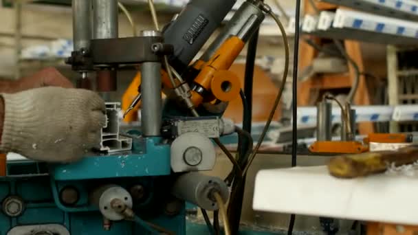 Produktion und Herstellung von PVC-Fenstern, männliche Arbeiter bohren Löcher auf einer Bohrmaschine in einem PVC-Profil für die Herstellung eines PVC-Fensters, Nahaufnahme, Werkzeugmaschine — Stockvideo