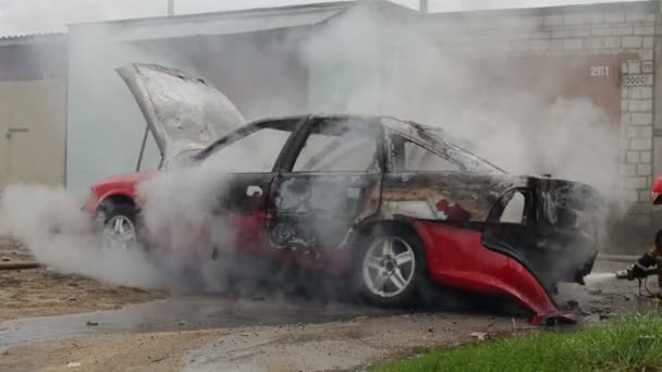 BOBRUISK, BELARUS - JULY 25, 2018: firefighters or firemen extinguish burnt car after act of terrorism — Stock Video