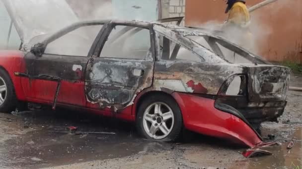 Bomberos con manguera apagar un coche quemado de pasajeros, vehículo no seguro — Vídeos de Stock