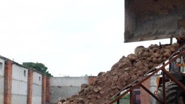 Büyük bir yükleyici kepçe kum kum taşlardan ayırmak için tohum matkap üzerinde taşlarla dışarı dökülen sower