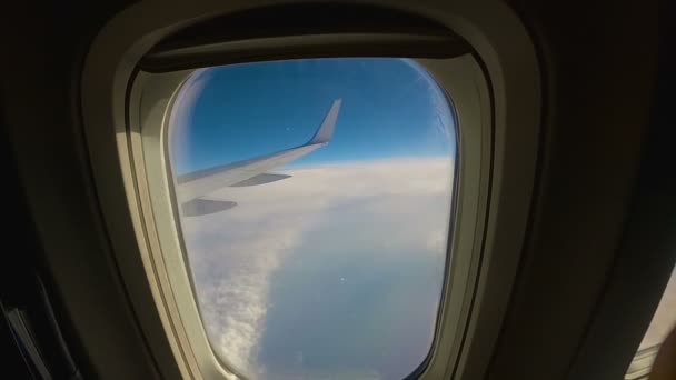 Самолет пролетает над облаками, вид через окно в крыло пассажирского самолета — стоковое видео