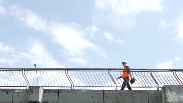 Ένας άνθρωπος επιθεωρητής βόλτες σε όλη την γέφυρα κοιτάζοντας γύρω και ελέγχει την ποιότητα της γέφυρας, έλεγχοι, μηχανικός — Αρχείο Βίντεο