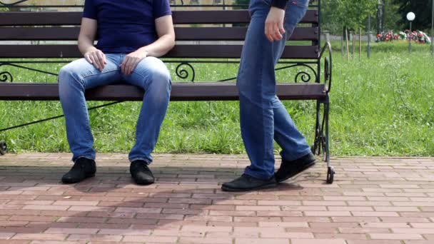 一个男人坐在城市的长凳上, 另一个男人走近, 他们在腿上互相抚摸, 牵着手离开, 同性恋, 同性恋 — 图库视频影像