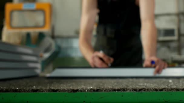 Производство ПВХ окон из профиля, мужчина работник отмечает размеры на профиле ПВХ, для дальнейшей сборки окна ПВХ, производственный маркер — стоковое видео