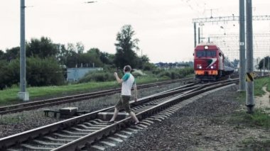 Adam kulaklıklarla geçer bir rairoad hareket eden trenin önünde aracılığıyla hayatı tehdit edici