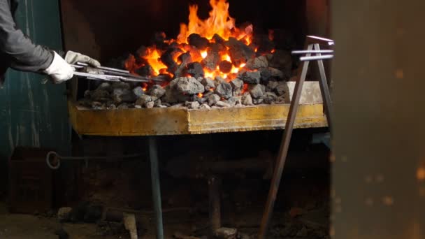 Un herrero invierte las partes de metal al rojo vivo en el horno, tratamiento térmico, endurecimiento y calentamiento de metal, forja, cámara lenta, herrero — Vídeo de stock