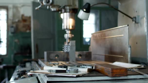 Een privé workshop voor het werken met metalen onderdelen, op de achtergrond een boren machine boren een gat in de riemschijf, op de leugen van de tabel meetgereedschappen, productie — Stockvideo