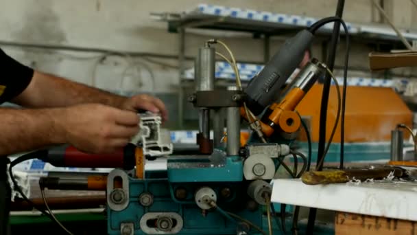 Producción y fabricación de ventanas de pvc, taladros de trabajadores masculinos en una máquina de perforación en un perfil de pvc para la fabricación de una ventana de pvc, primer plano, taladro de banco — Vídeo de stock