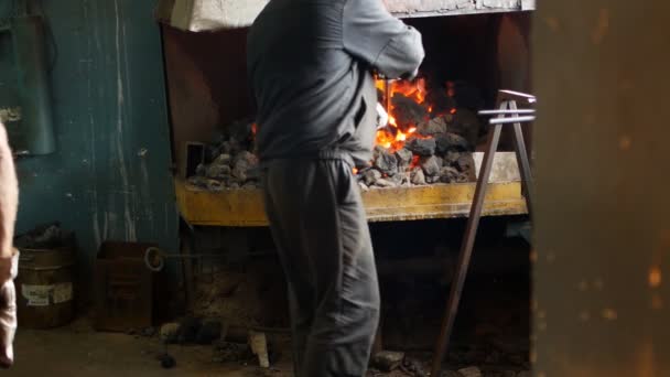 Un herrero invierte las partes de metal al rojo vivo en el horno, tratamiento térmico, endurecimiento y calentamiento de metal, forja, cámara lenta, herrero — Vídeo de stock