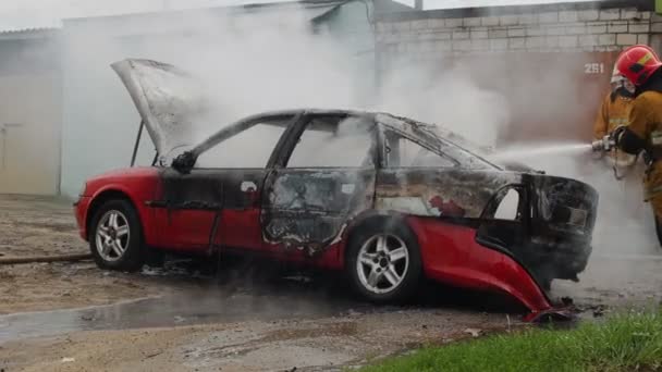 BOBRUISK, BELARUS - JULY 25, 2018: firefighters or firemen with hose extinguish a burning car after autoignition — Stock Video