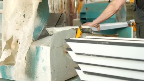 Production de fenêtres en pvc, l'homme installe un profil en pvc dans la machine de découpe et le coupe pour s'adapter à un montage ultérieur de la fenêtre en pvc, l'industrie de la découpe — Video