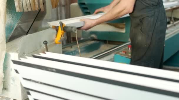 Produção de janelas de pvc, o homem instala um perfil de pvc na máquina de corte e corta para caber para posterior montagem da janela de pvc, cortando — Vídeo de Stock
