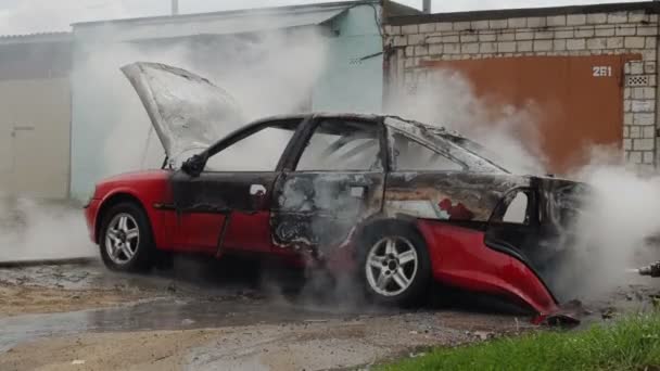 БОБРУИСК, БЕЛАРУС - 25 июля 2018 года: пожарные или пожарные тушат сожженный автомобиль после террористического акта — стоковое видео