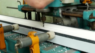 Üretim ve üretim pvc pencere, pvc profil yükler bir kadın işçi pvc gövde kolu, yakın çekim, matkap altında bir delik makinesi ve matkaplar
