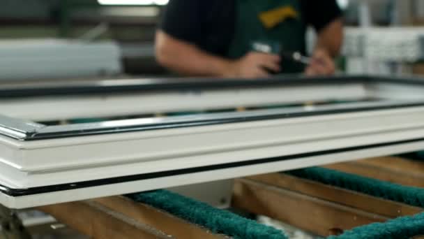 Produção e fabricação de janelas de pvc, o trabalhador masculino monta uma janela de perfil de pvc, prende as peças articuladas, janela de pvc, janela de pvc de montagem de chave de fenda — Vídeo de Stock
