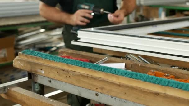 Producción y fabricación de ventanas de pvc, el trabajador masculino monta una ventana de perfil de pvc, sujeta las piezas con bisagras, ventana de pvc, ventana del destornillador — Vídeo de stock