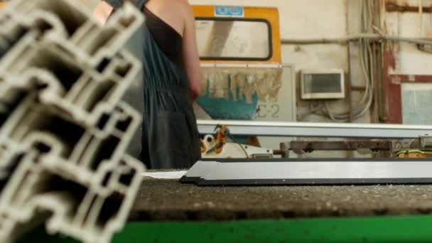 Produção de janelas de pvc, o homem instala um perfil de pvc na máquina de corte e corta-o para caber para posterior montagem da janela de pvc, janela de fabricação — Vídeo de Stock