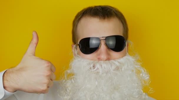 Portrait d'homme barbe blanche et lunettes noires, pouces levés, émotion humaine drôle et joyeuse, sur fond de mur jaune — Video