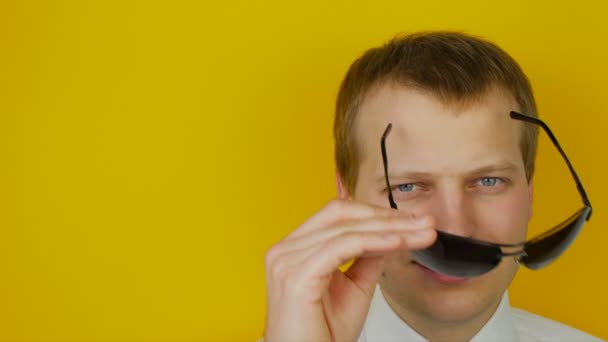 Portrét usmívající se muž v bílé košili s černými brýlemi, na pozadí žluté zdi — Stock video
