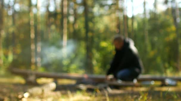 Un hombre enciende un fuego en el bosque en la naturaleza, recreación al aire libre, borroso, fondo, camping — Vídeos de Stock