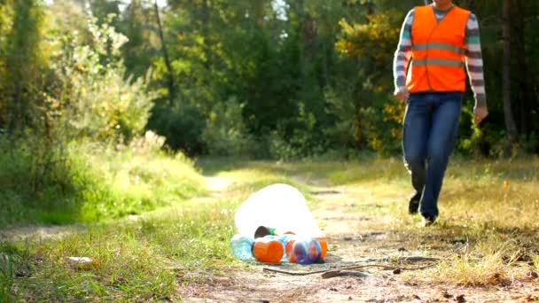 Männliche freiwillige Reinigungskraft in der signalorangefarbenen Weste reinigt Müll im Wald, reinigt Wald und Natur von Müll, Müll und Natur, Müll — Stockvideo