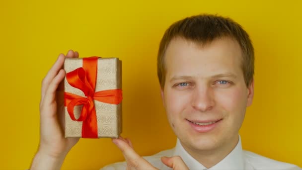 Guy with surprise inside the box smiles and looks into the camera, on yellow wall background — Stock Video