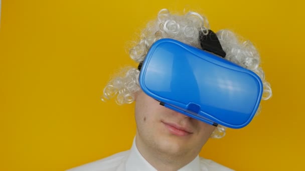 Krullend grappige man met witte haren in virtual reality headset, komisch en vrolijk menselijke emotie, op gele muur achtergrond — Stockvideo