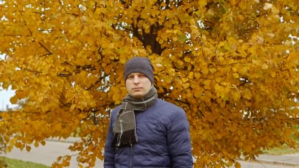 Портрет чоловіка, що стоїть біля дерева восени або восени на відкритому повітрі або зовні — стокове відео