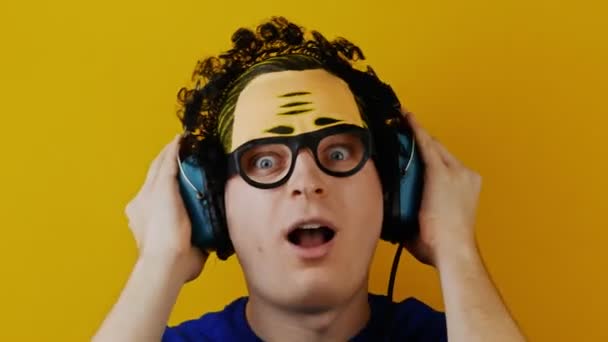 Galen komisk lockig kille lyssnar på musik i en retro hörlurar — Stockvideo