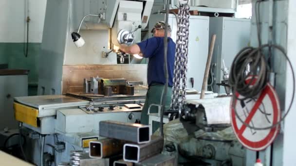 Ένας άνθρωπος που ειδικεύεται driller τρύπες σε μια μηχανή διατρήσεων σε ένα μεταλλικό κομμάτι προς κατεργασία, μια μικρή επιχείρηση, ιδιωτικό εργαστήριο, πάγκος — Αρχείο Βίντεο