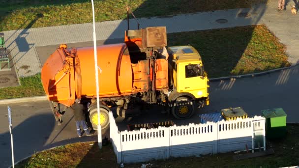 Un camión de basura limpia los botes de basura en el patio de una zona residencial de la basura y lo lleva al vertedero, camión de basura — Vídeo de stock