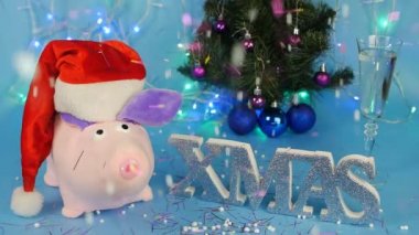 Yumuşak oyuncak pembe domuz mavi arka plan, bir kadeh şampanya, bir Noel ağacına arka plan üzerinde kırmızı bir Noel Baba şapkalı bir sineklik patlar ve yeni yıl tinsel düşüyor, şeker, xmas, uyuşuk