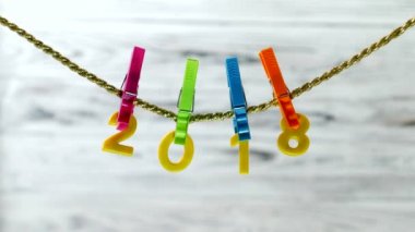 Sarı numaraları 2018 asılı bir ip üzerinde bir ahşap arka plan, yakın çekim, el üzerinde bir clothespin 2018 2019, yedek değiştirir