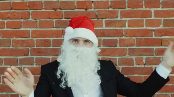 Hombre como un Santa Claus está bailando, Feliz Navidad y Año Nuevo 2019, pared de ladrillo rojo como fondo — Vídeos de Stock