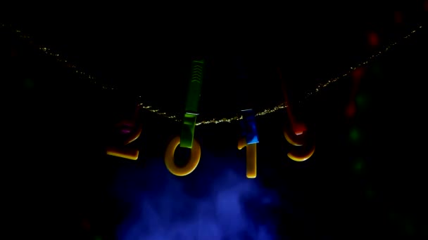 Számok 2019 lóg a clothespins és egy kötelet, amelyek alapján van gőz füst, a háttérben Szilveszter jelzőfények égnek, az új évben 2019, karácsony — Stock videók