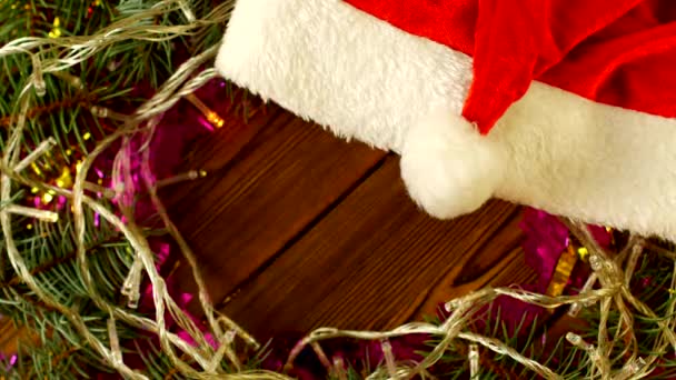 Vánoční osvětlení a smrkové větve na dřevěné pozadí a červený klobouk Santa Clause, nový rok 2019, Vánoce, místo pro nápis, dekorace, kopírovat prostor, Vánoce — Stock video