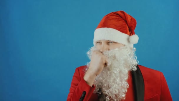 Navidad y Año Nuevo, se preguntó el hombre como un Santa piensa y reflexiona, sobre fondo azul — Vídeos de Stock