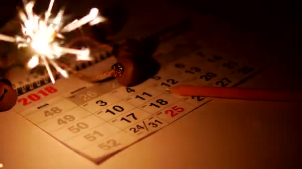 On the table is a calendar with holiday dates New Years holidays, sparklers are burning and a pencil is lying, Xmas, new Year, close-up, december — Stock Video