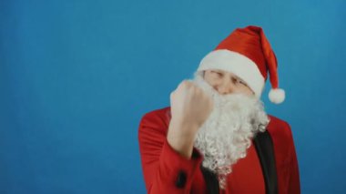 Noel ve yeni yıl 2019, Noel Baba gibi adam kameraya mavi arka plan, yumruk gösterir