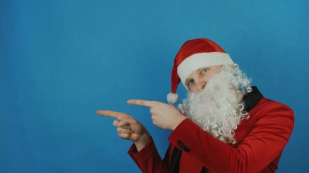 Natale e Capodanno, l'uomo come un Babbo Natale indica un luogo di testo, spazio di copia, su sfondo blu — Video Stock