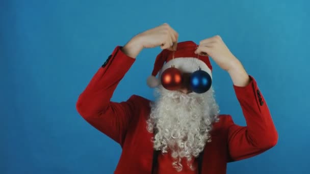 新年, 男人就像一个圣诞老人与红色和蓝色的圣诞球小球玩具, 在蓝色的背景 — 图库视频影像