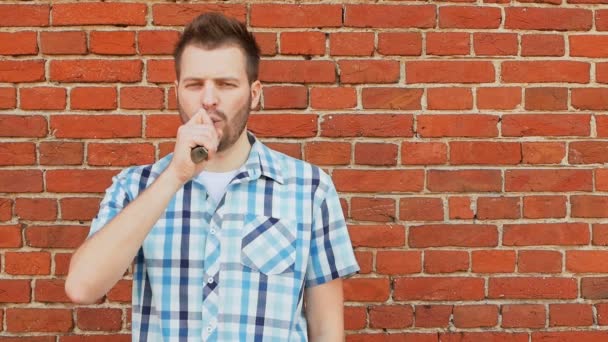 Bearded man smoking an electronic cigarette and blows a cloud of vapor — Stock Video