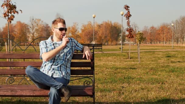 Bearded man smoking an electronic cigarette and blows a cloud of vapor — Stock Video