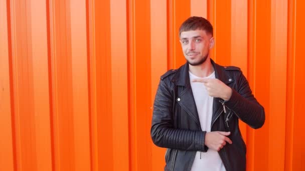 Young man shows his finger on the empty space on an orange background, close-up, copy space, slow motion — Stock Video