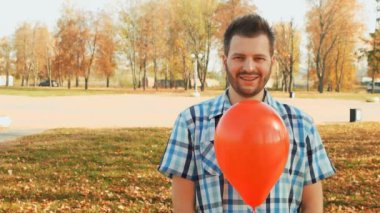 gülümseyen adam standları elinde kırmızı bir balon ile sakallı